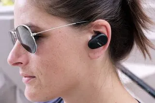 A side headshot of a woman wearing Sony’s SP-800N earbuds.